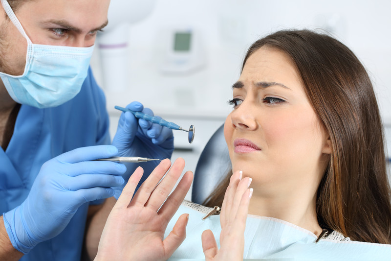 Anxious woman showing fear of dental tools, highlighting dental anxiety addressed through sedation dentistry in Austin, TX.